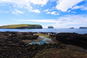 Pohled na ostrov Surtsey  z pláže na ostrově Vestmannaeyjar – elleon / Shutterstock