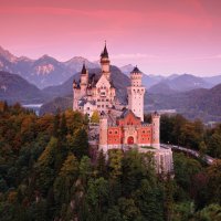 Hrad Neuschwanstein, s podzimními barvami po západu slunce, Bavorské Alpy v Bavorsku, Německo – Ondrej Prosicky / Shutterstock